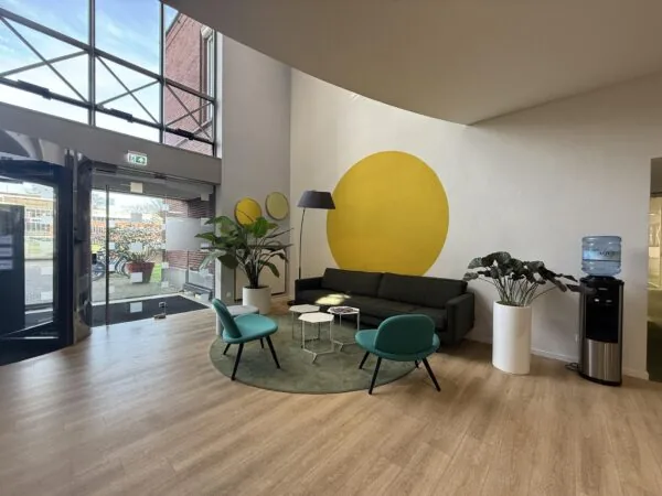 Moderne wachtruimte aan de Arnhemse Bovenweg met kleurrijk interieur, planten en een grote gele cirkel op de muur.